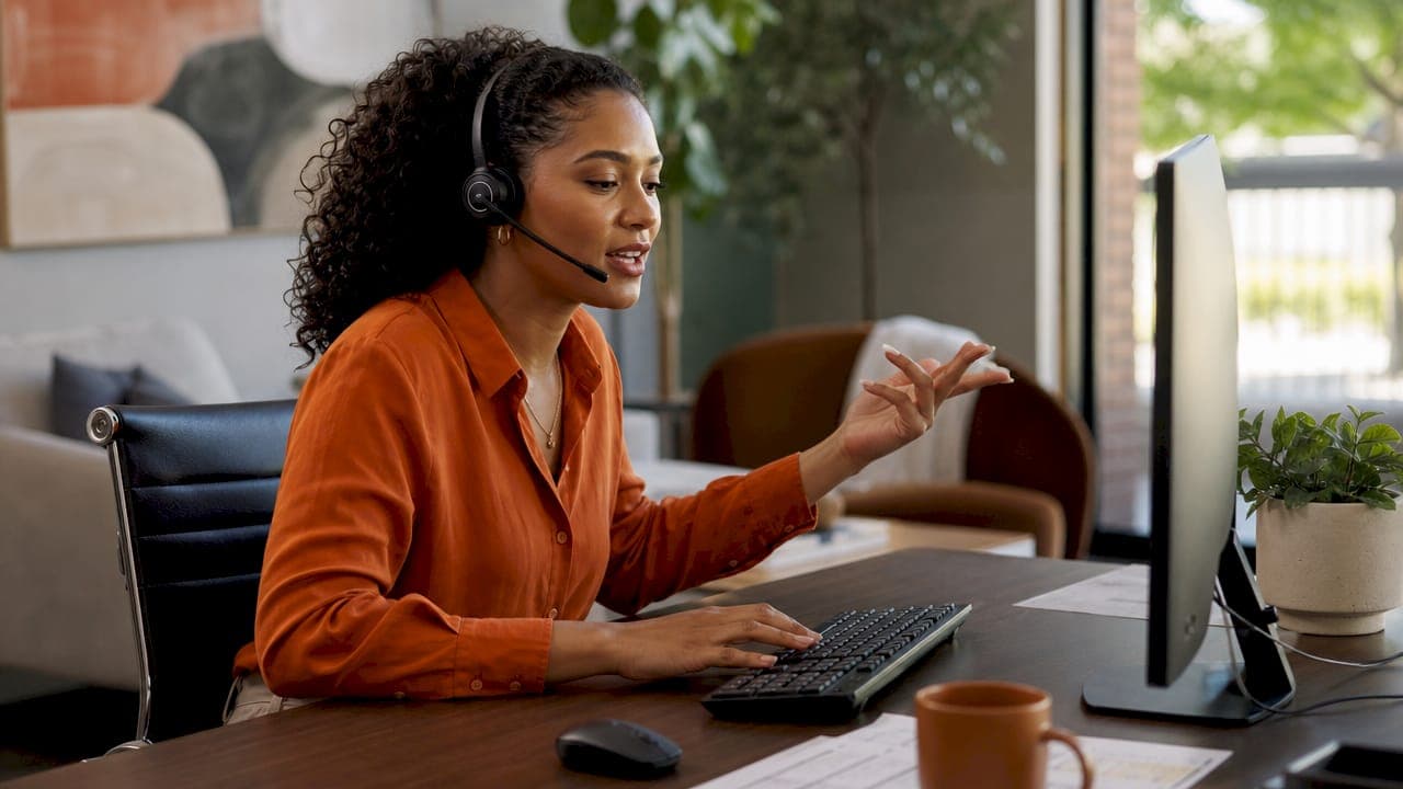 Leasing agent typing with headset at office desk