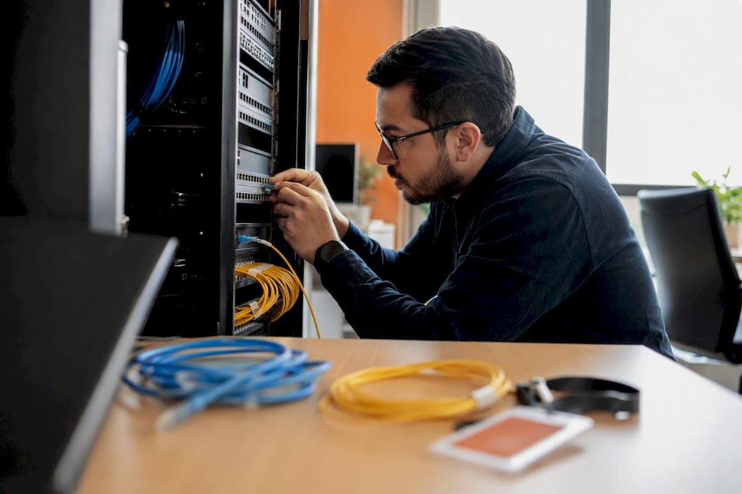 Engineer plugging fiber optic cable in server room