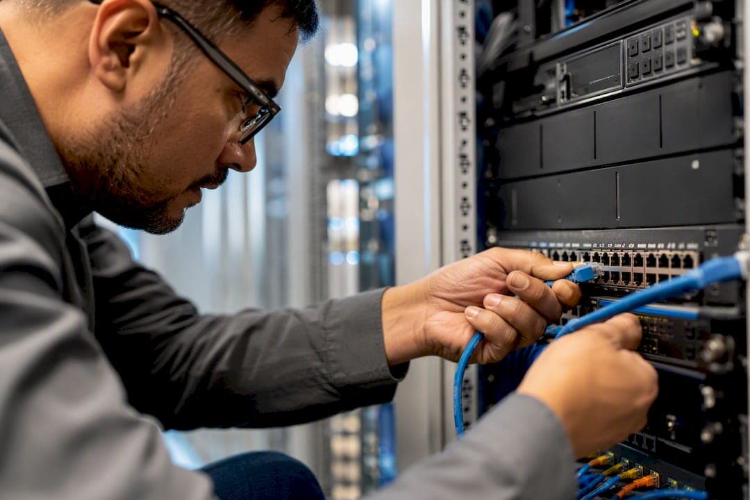 Hands unplugging network cable in server room