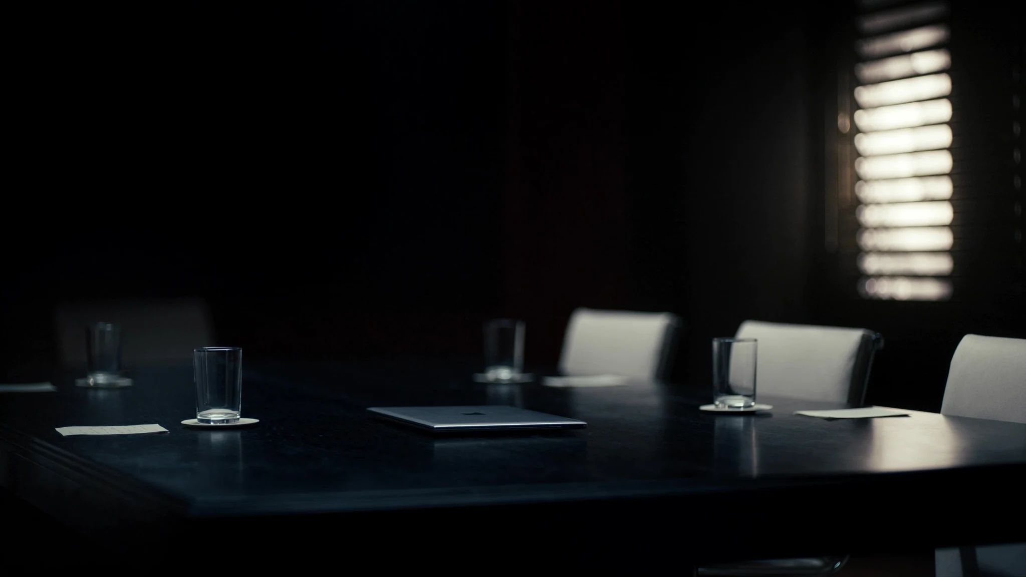 After-hours conference table in an agri-food office, laptop and coffee waiting for a decision that has no owner
