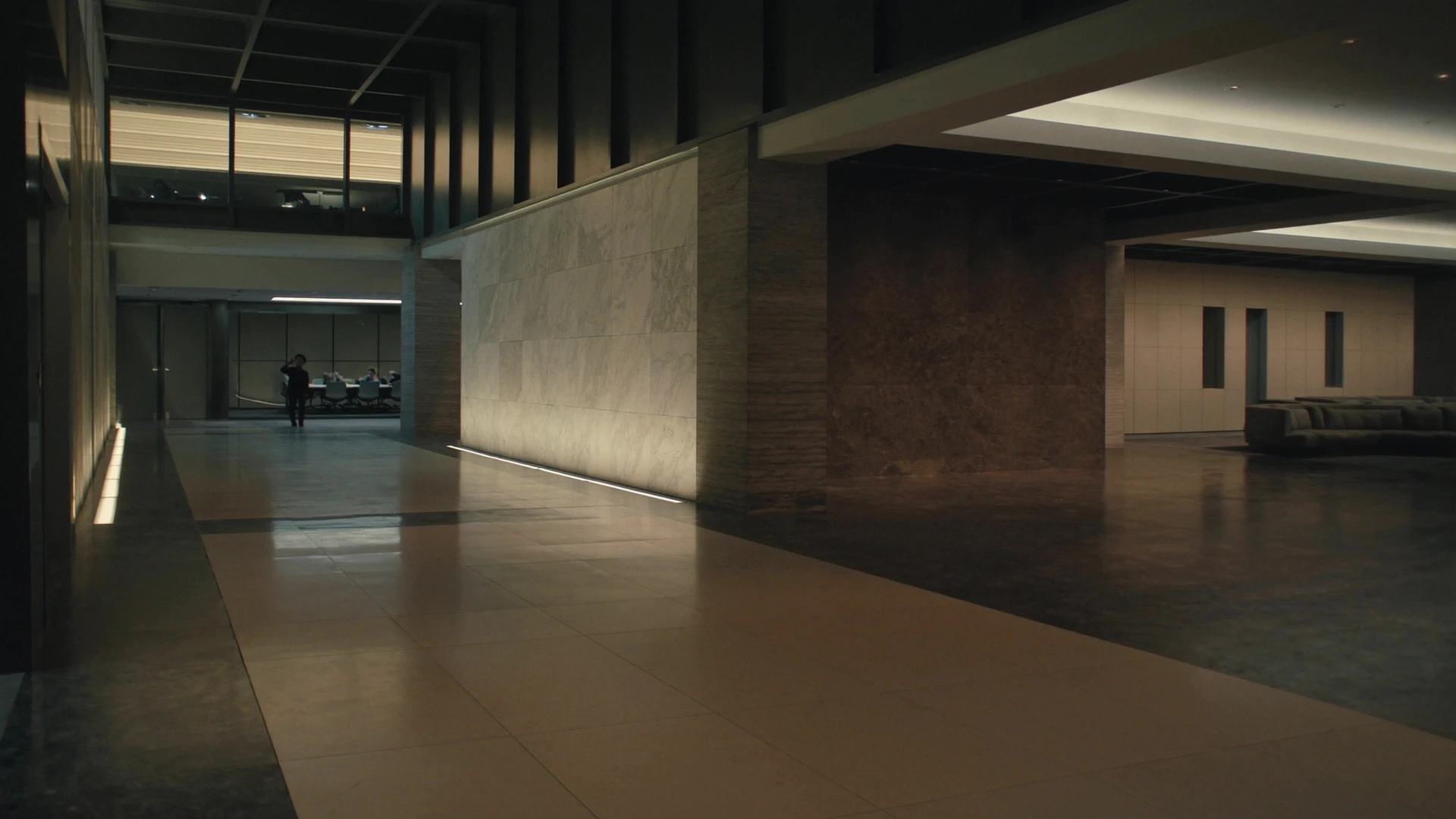 Dark architectural lobby at night, a corridor of light toward the rooms where decisions are made