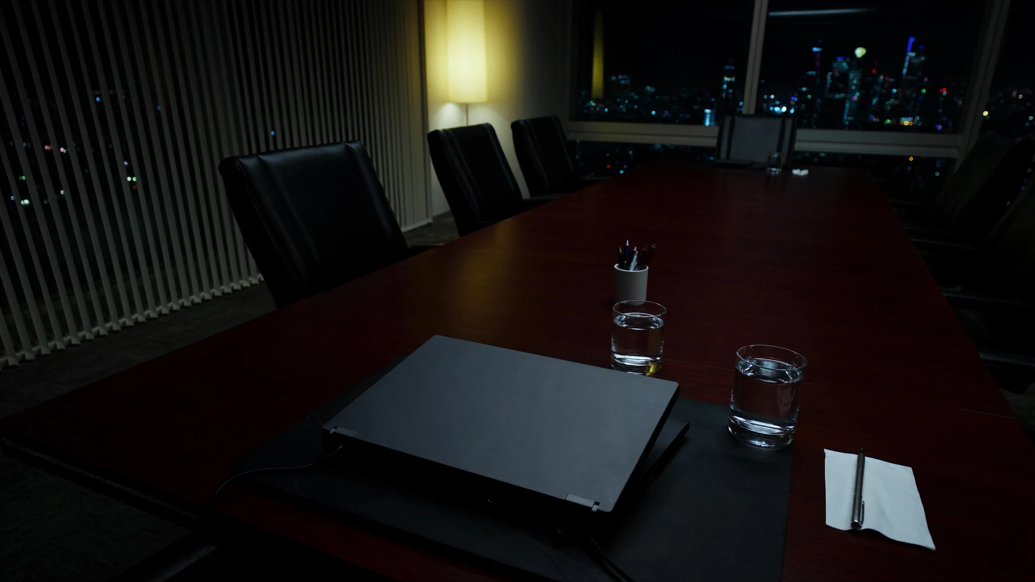 After-hours conference table in an energy office, laptop and espresso waiting for a decision that has no owner