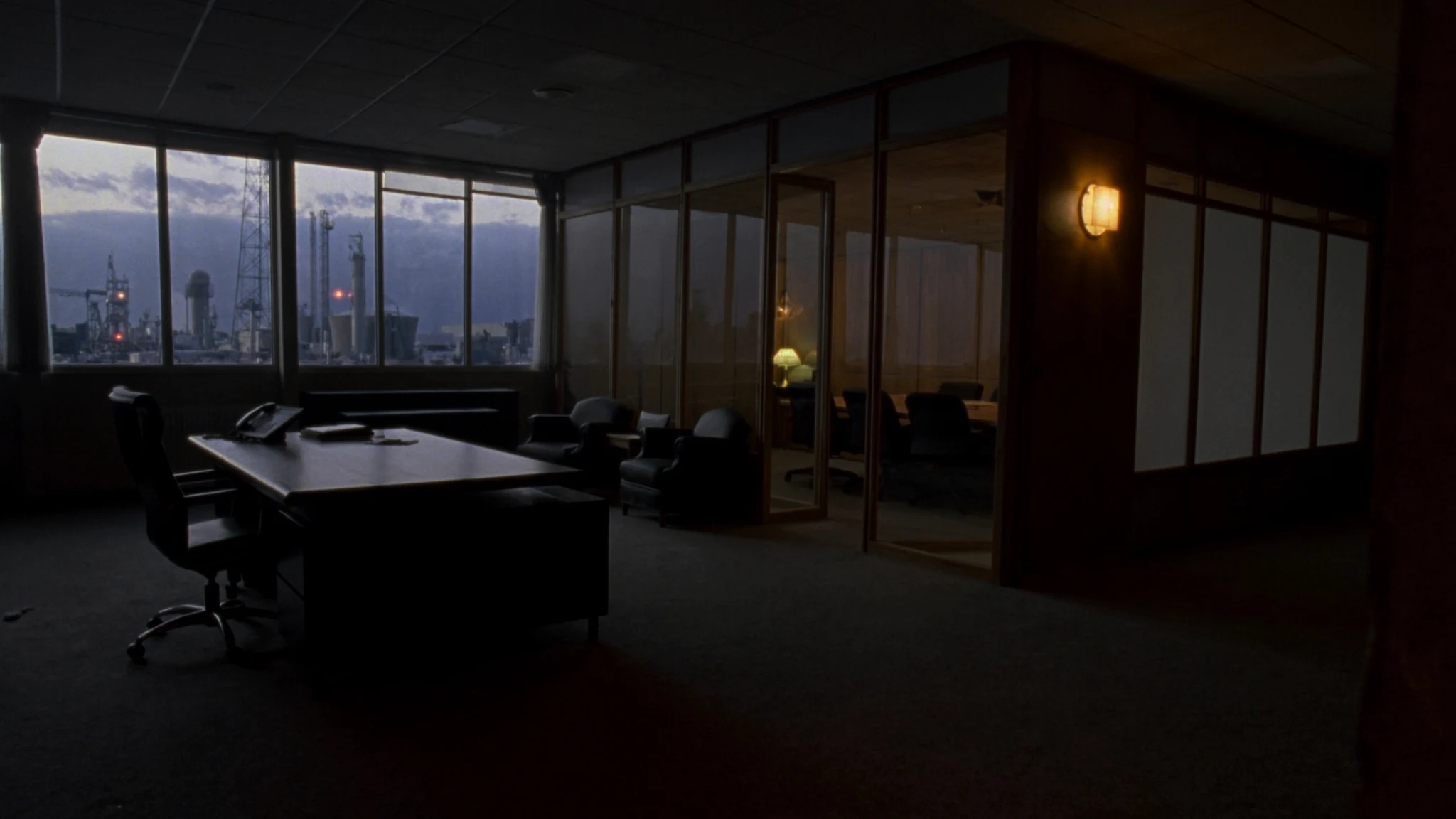 After-hours corridor in a plant headquarters, a single chair outside the rooms where the AI function is decided