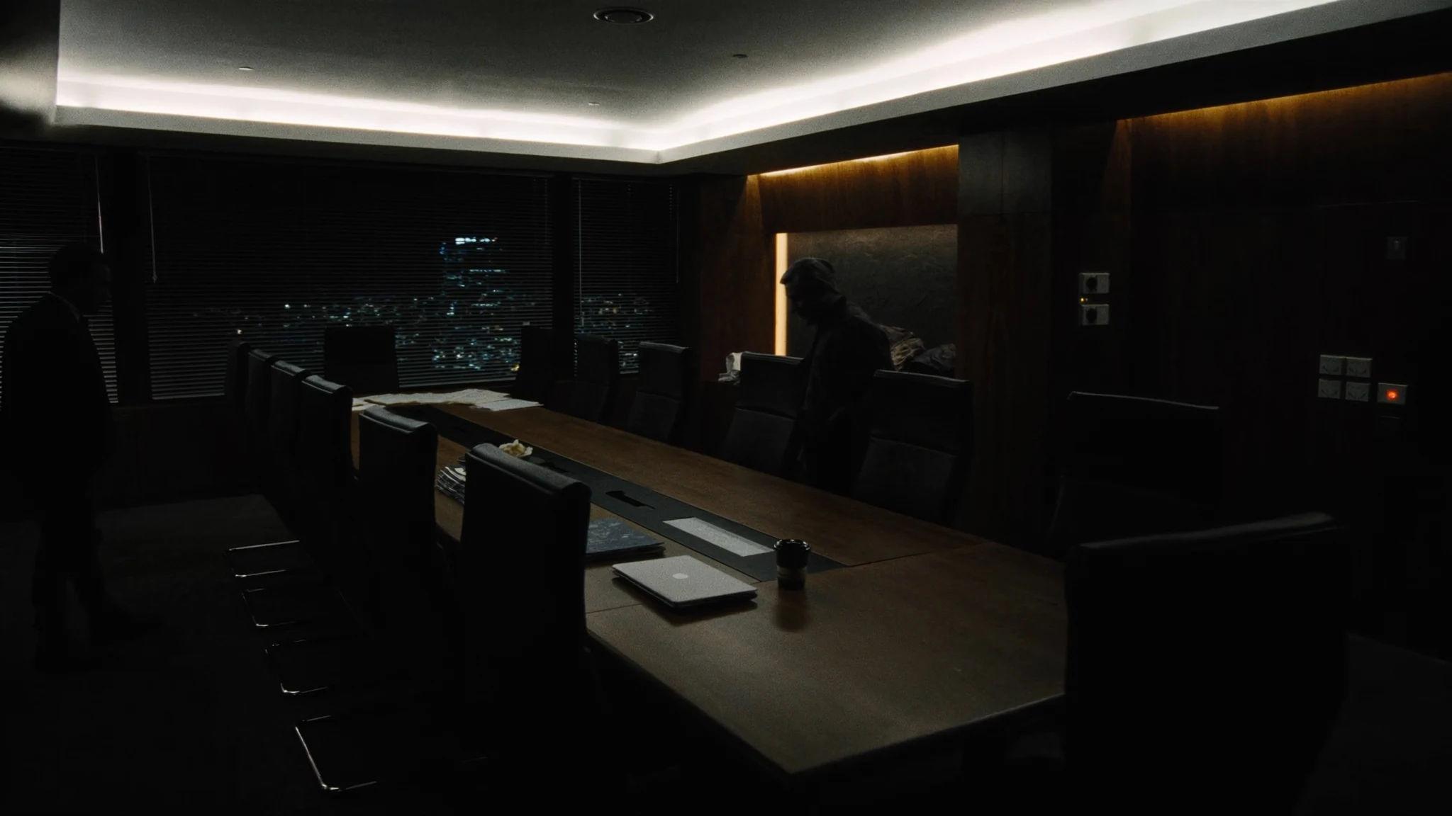 After-hours conference table in an insurance office, laptop and espresso waiting for a decision that has no owner
