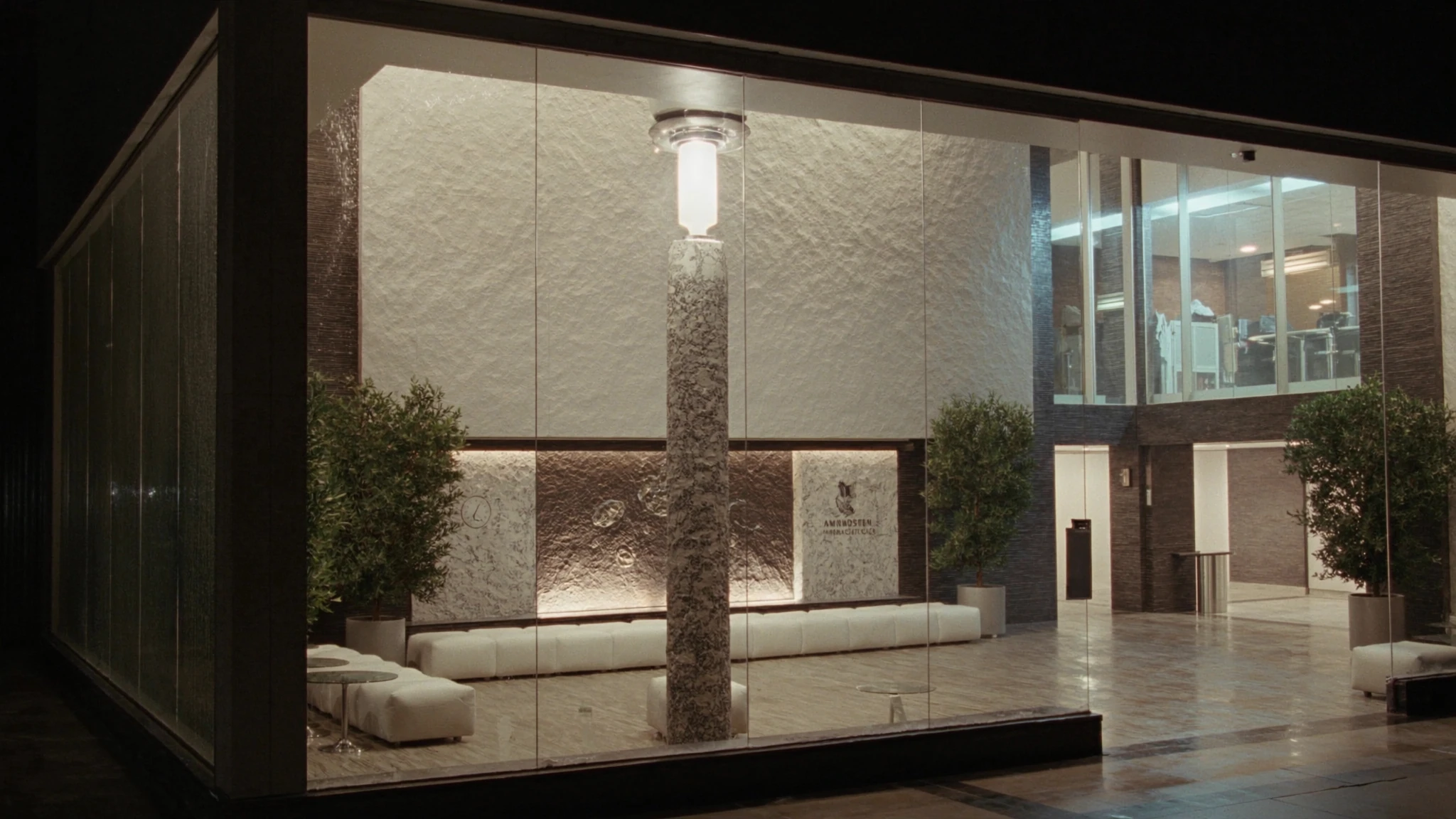 Night view into a pharmaceutical headquarters lobby, a corridor of warm light toward the rooms where decisions are made