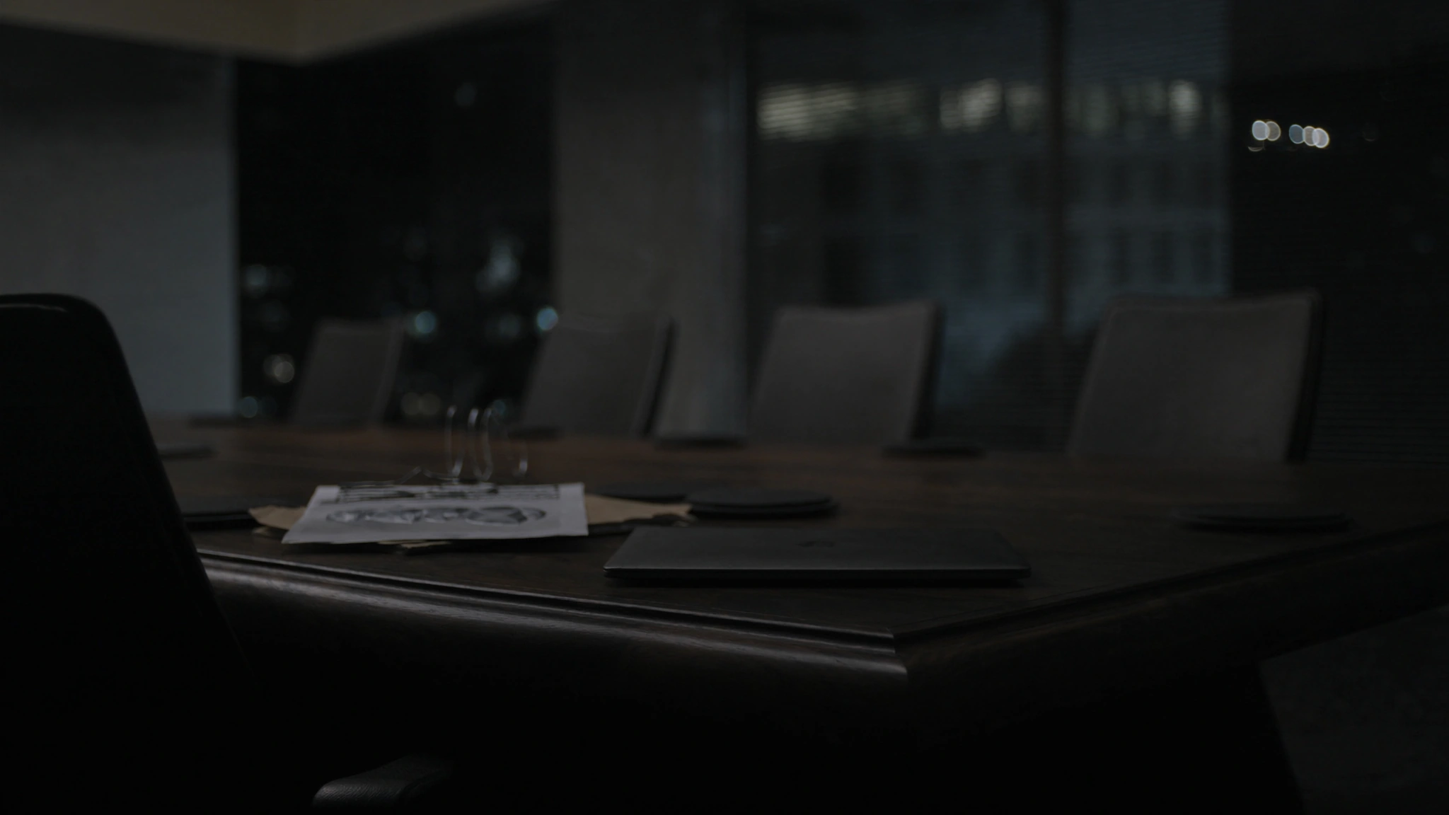 After-hours conference table in a pharmaceutical headquarters, laptop and espresso waiting for a decision that has no owner