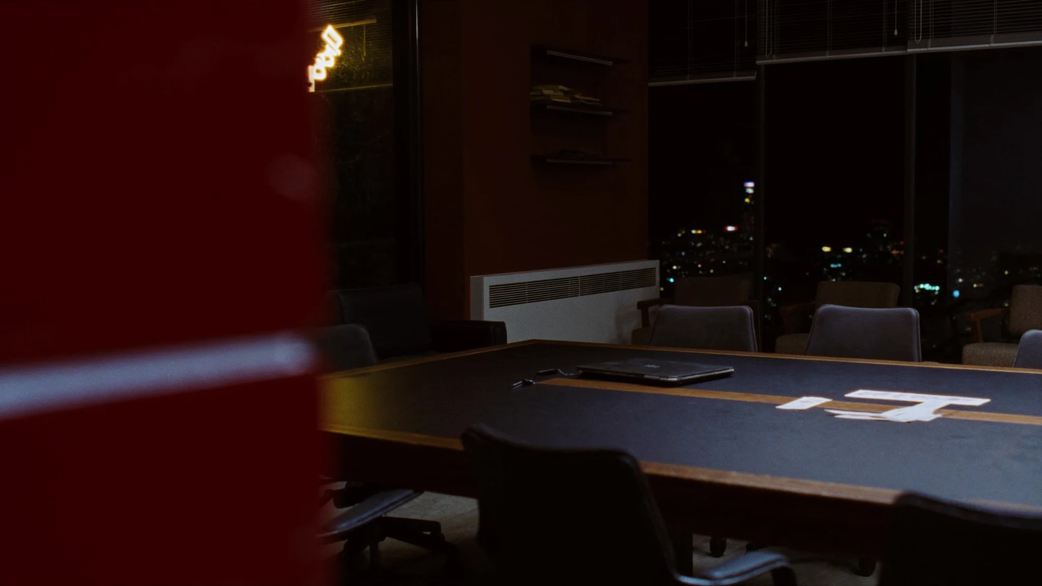After-hours conference table in a retail office, laptop and coffee waiting for a decision that has no owner